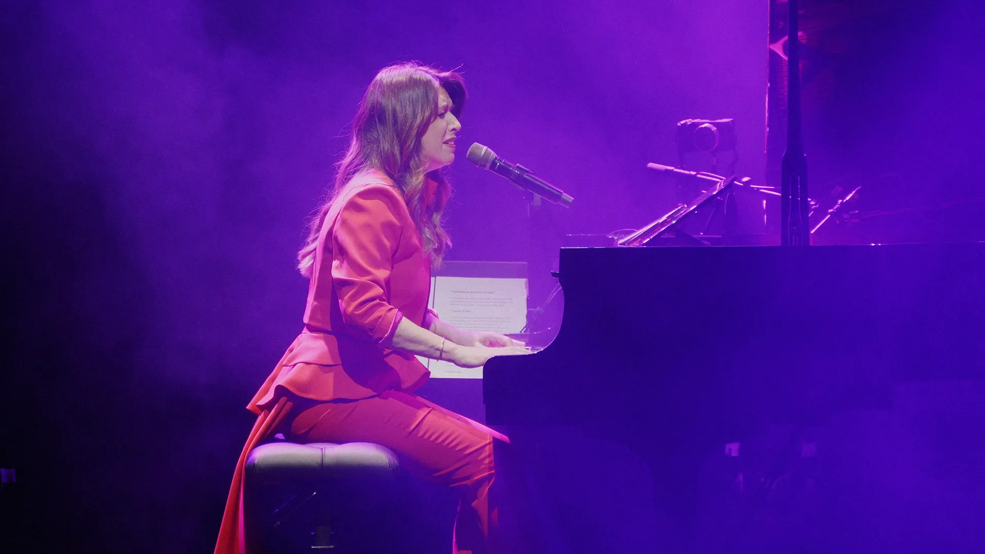 Maria Ana Bobone canta ao piano, luz violeta